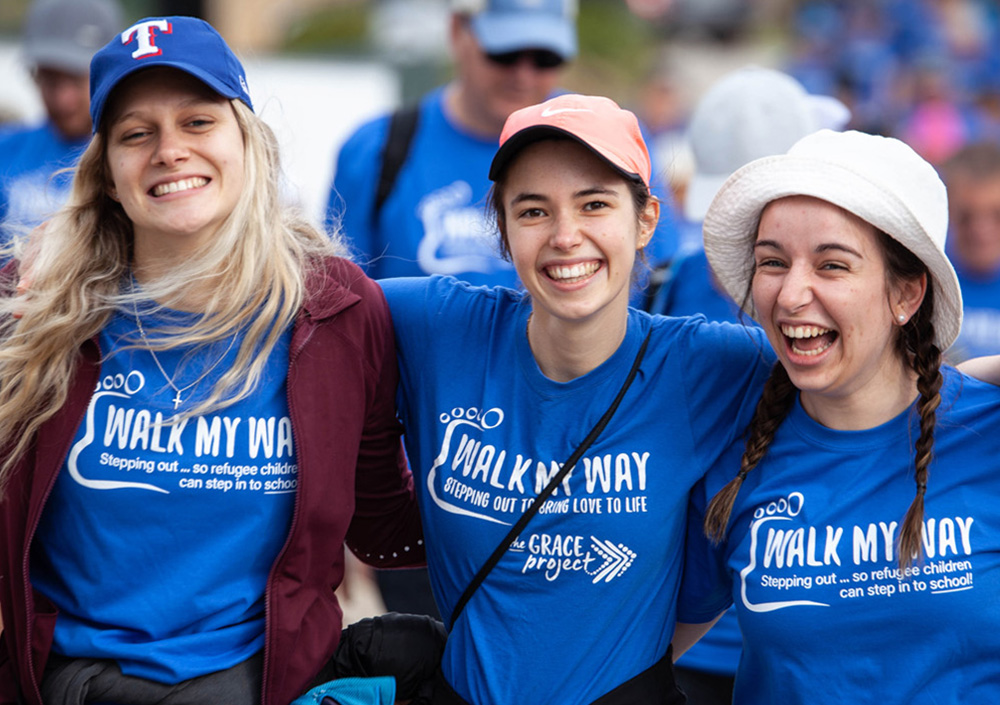 Three smiling women in blue Walk My Way shirts at a WMW event